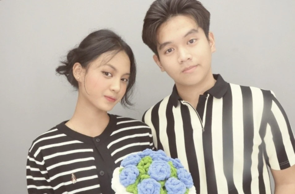 Sasha and Fakhri in striped tops with a blue bouquet.