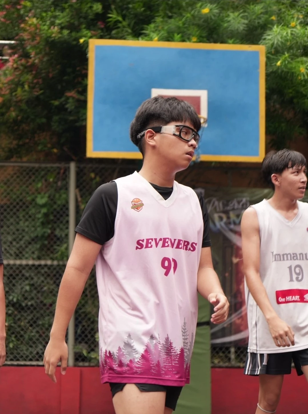 Fakhri on the basketball court in a pink jersey and sports glasses.